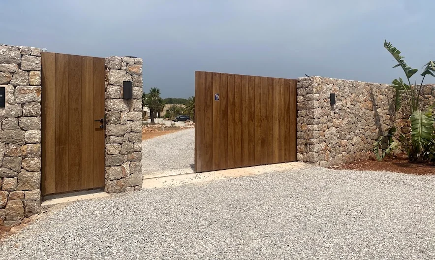 Property entrance with stone walls and wooden gates