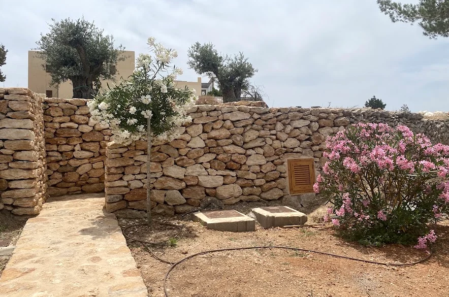 Stone wall with a garden path and oleanders at a property in Ibiza